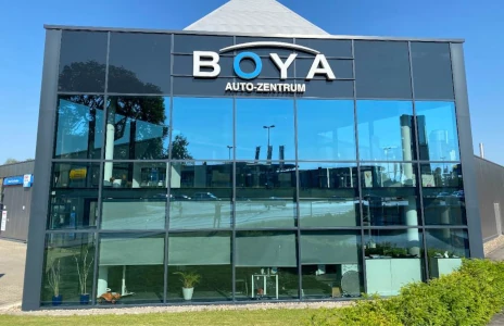 Glasfassade des Autohauses BOYA Auto-Zentrum mit Eingang und Reflexionen
