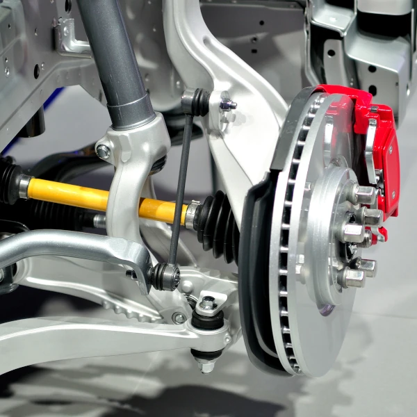 Moderne Autoaufhängung mit Bremsscheibe und rotem Bremssattel in Nahaufnahme.