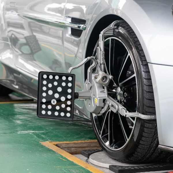 Radauswuchtung und Achsvermessung an einem silbernen Auto in der Werkstatt.
