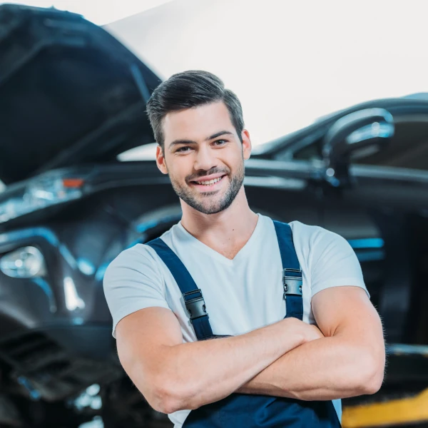 Kfz-Mechaniker prüft konzentriert den Motor eines Autos in einer modernen Werkstatt.